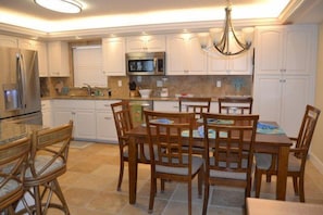 A kitchen with white cabinets, a dining table with chairs, and a chandelier. - #604 Sandcastle 2/2 Oceanfront condo - Traffic Free Beach (Ponce Inlet)