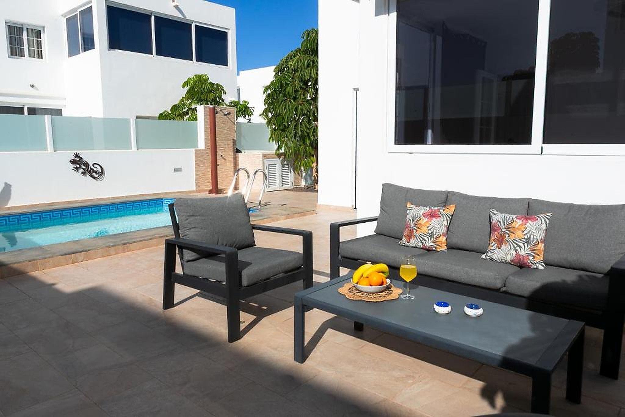 Un espace extérieur moderne aménagé avec un coin salon, une piscine, un canapé et une table basse.