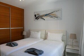 Ett hotellrum med en dubbelsäng, två sängbord med lampor, en garderob i trä och en stor, abstrakt målning på väggen.