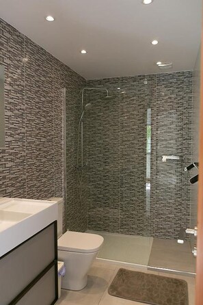 A modern bathroom with a glass shower enclosure, a white toilet, and a sink area. - Casa Sirius-Private Pool by Lanzarote Vacation Homes (Playa Blanca)
