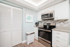 Una cocina moderna con armarios blancos, horno de acero inoxidable, microondas y salpicadero de azulejos.