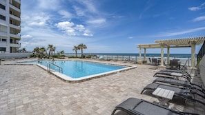 A swimming pool with a view of the beach, lounge chairs, and a covered seating area. - Seychelles 605  2/2 Direct Oceanfront condo (Daytona Beach Shores)