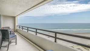 A balcony with wicker furniture overlooking a beach. - Seychelles 605  2/2 Direct Oceanfront condo (Daytona Beach Shores)