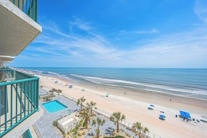 Ein Hotel direkt am Strand mit Pool, Strandliegen und Palmen.