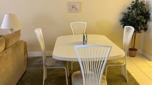 Un coin repas avec une table ronde et quatre chaises, une lampe, un canapé et une plante en pot.