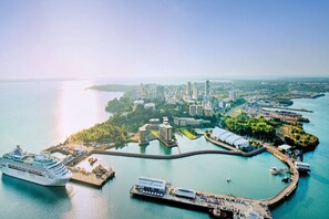 A cruise ship docked at a port with a cityscape in the background. - Tropical City 1-Bed Apartment Near Waterfront (Darwin City)
