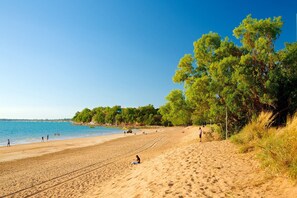 A beach with a clear sky, sandy shore, and trees. - Central Darwin 1-Bed Retreat Near Attractions (Darwin City)