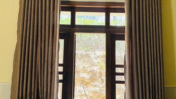 Cuina amb finestra, cortines, una papereta, safates amb plats i un suport amb gots.