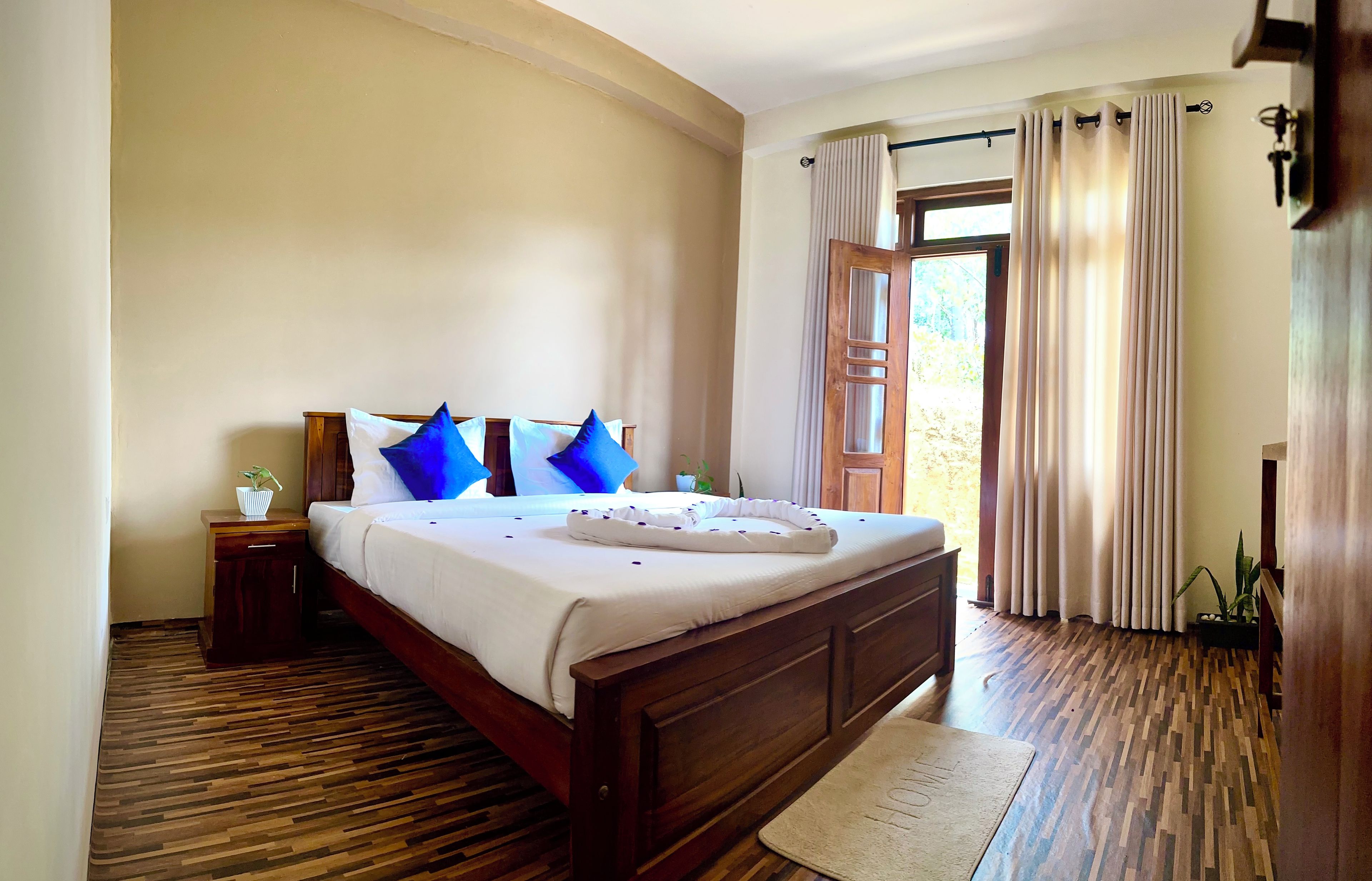 A bedroom with a wooden bed, white bedding, and blue pillows.