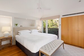 Une chambre à coucher comprenant un lit, une table de chevet, un banc, une armoire et un ventilateur de plafond.