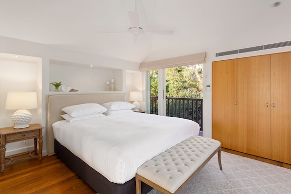 A bedroom with a bed, bedside table, bench, wardrobe, and a ceiling fan. - Waterfall Garden 3-Bed Home McMahons Point (McMahons Point)