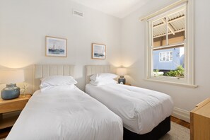 A hotel room with two beds, a window with a view, and two framed pictures on the wall. - Waterfall Garden 3-Bed Home McMahons Point (McMahons Point)