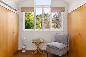 A room with a window, a chair, a table, and a radiator. - Waterfall Garden 3-Bed Home McMahons Point (McMahons Point)