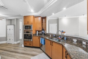 A modern kitchen with granite countertops, stainless steel appliances, and wooden cabinets. - 707 Bella Vista in Daytona Beach Shores, FL (Daytona Beach Shores)