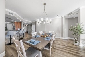 A dining area with a wooden table, white chairs, and a chandelier. - 707 Bella Vista in Daytona Beach Shores, FL (Daytona Beach Shores)