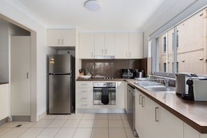 A modern kitchen with stainless steel appliances, a built-in oven, and a dishwasher. - Beachside 2-Bed Apartment in Coogee (Coogee)