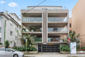 A multi-story residential building with balconies, a garage, and a 'For Sale' sign. - Beachside 2-Bed Apartment in Coogee (Coogee)