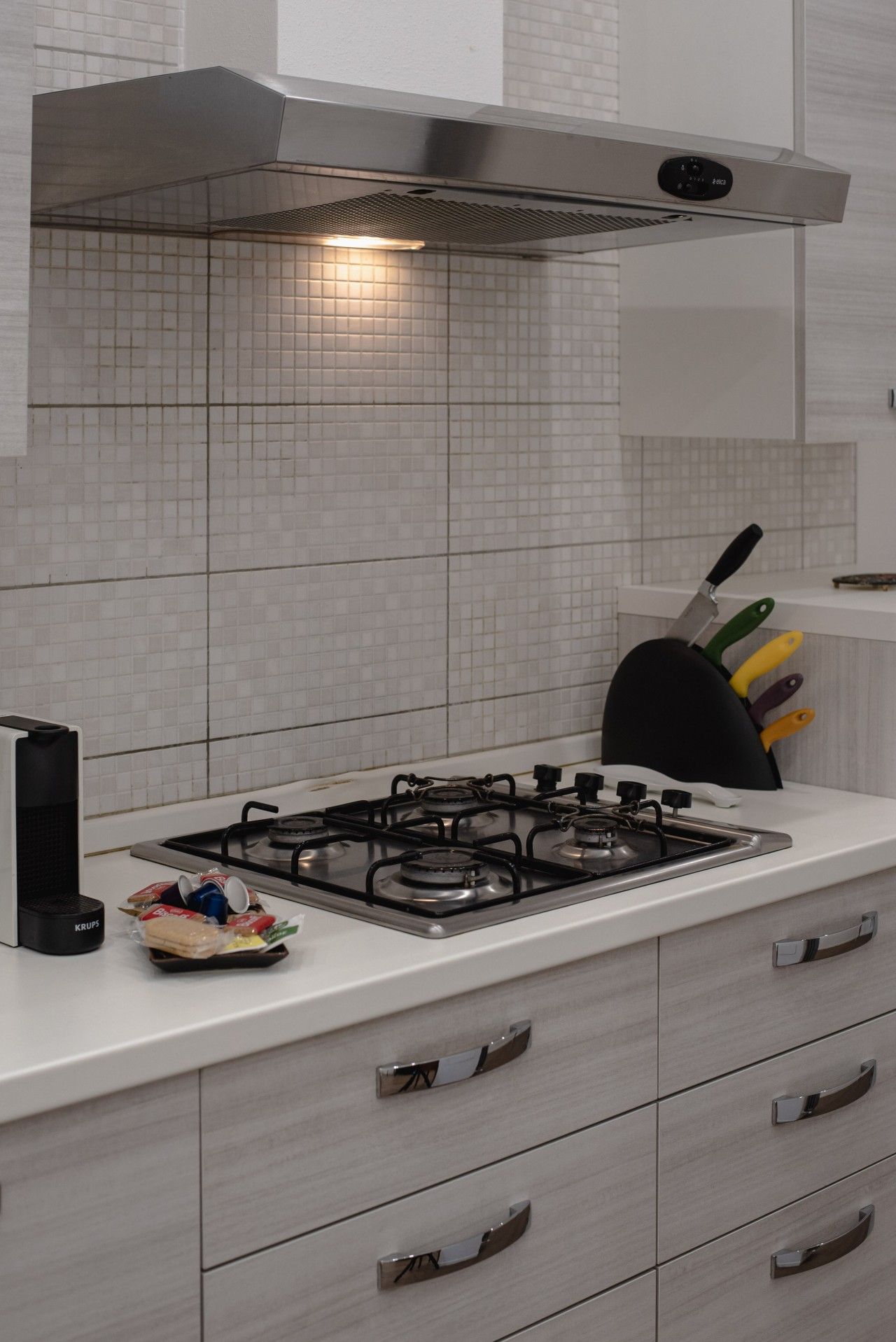 Una cucina con piano cottura a gas, cappa aspirante e un portachiodi.