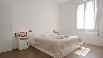 A minimalist bedroom with a bed, bedside tables, and a window.