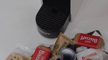 Eine Auswahl verpackter Kekse, eine Kaffeemaschine und einige Tassen auf einem Tisch.