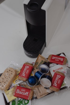 Eine Auswahl verpackter Kekse, eine Kaffeemaschine und einige Tassen auf einem Tisch.