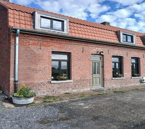 A brick building with a tiled roof, a door, and windows. - 3-Bedroom Country Cottage at Chez Violette (STEENBECQUE)