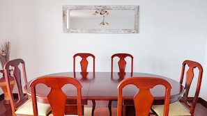 A dining table with four chairs, a vase with dried plants, and a mirror on the wall. - Vale Formoso Funchal by Rentallido (Funchal)