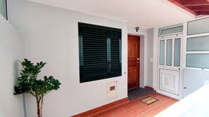 A hallway with a potted plant, a door, a window with shutters, and a tiled floor. - Vale Formoso Funchal by Rentallido (Funchal)