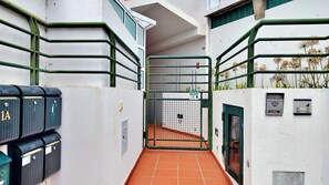 A narrow corridor with a green gate, mailboxes, and a security keypad. - Vale Formoso Funchal by Rentallido (Funchal)