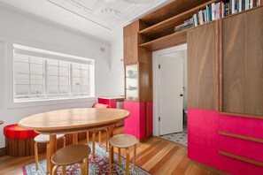 Eine moderne Küche mit einem Holzespeisetisch, Stühlen und einem leuchtend rosa Schrank.