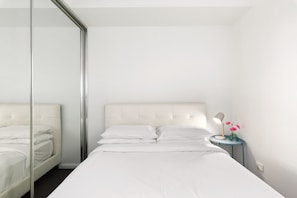 Une chambre moderne avec un grand lit, une table de chevet avec une lampe et un miroir.