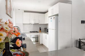 Une cuisine moderne avec des meubles blancs, une cuisinière en acier inoxydable et un réfrigérateur.