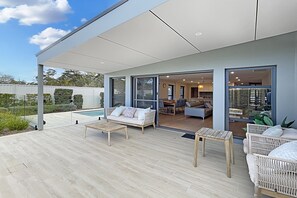 A modern outdoor living space with a pool, a covered patio, and a view into the interior. - Coastal Pool 3-Bed Townhouse Near Broulee Beach (Broulee)