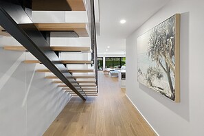 Ein modernes Interieur mit Treppe, Holzböden und einem großen Gemälde an der Wand.