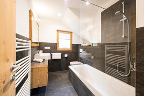 A modern bathroom with a bathtub, shower, and a wooden vanity. - Apartment 'Hütterhof Aschbach "Holunder"' with Mountain View and Wi-Fi (Lagundo)