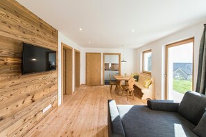 A modern interior with a wooden wall, a flat-screen TV, a dining area, and a sofa. - Apartment 'Hütterhof Aschbach "Holunder"' with Mountain View and Wi-Fi (Lagundo)