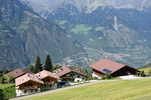 Ein Bergdorf mit traditionellen Holzhäusern, einer Pflasterstraße und Blick ins Tal.