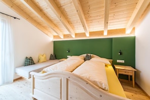 Ein Zimmer mit Holzboden, einer grünen Akzentwand, zwei Betten, Nachttischen und einem fenster mit Vorhängen.
