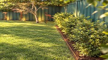 A well-maintained grassy area with a wooden planter box containing shrubs.