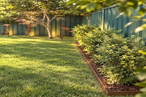 A well-maintained grassy area with a wooden planter box containing shrubs. - Garden 2-Bed Villa in the Heart of Bowral (Bowral)