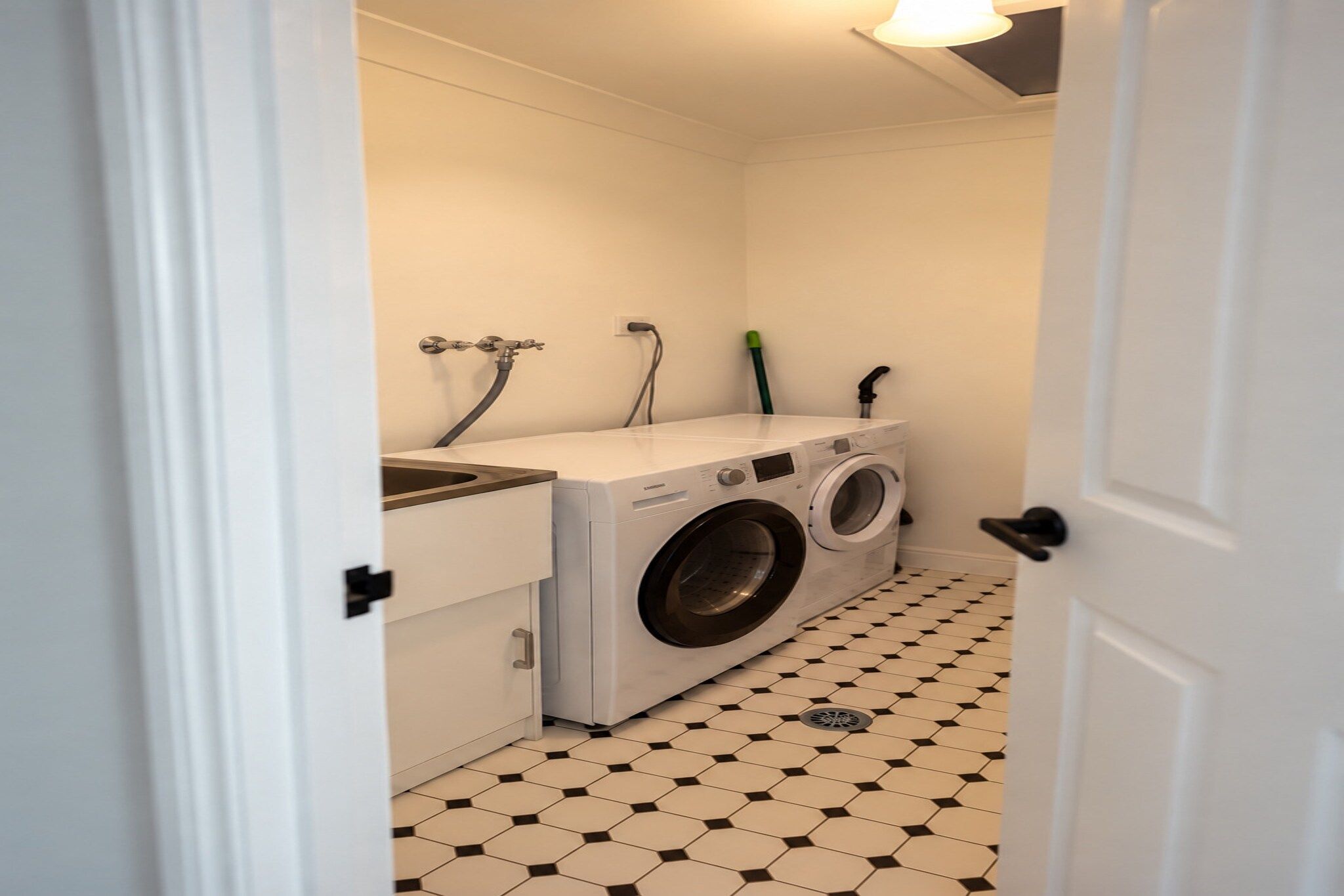 A laundry room with a washing machine and dryer, a tiled floor, and a white door.