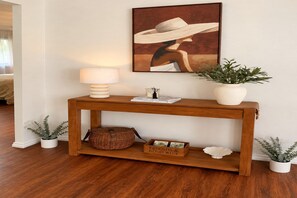 A wooden console table with a lamp, a framed artwork, and a potted plant. - Garden 2-Bed Villa in the Heart of Bowral (Bowral)