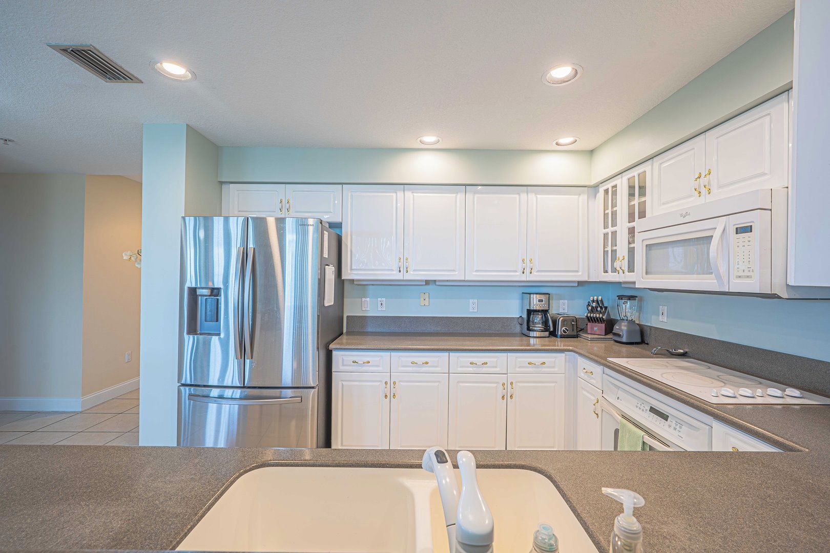 A modern kitchen with white cabinets, stainless steel appliances, and a granite countertop.