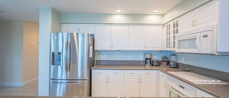 A modern kitchen with white cabinets, stainless steel appliances, and a granite countertop.