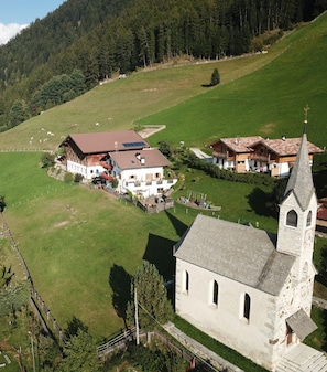 Ländliche Landschaft mit einer Kirche, Bauernhäusern und weidenden Tieren.