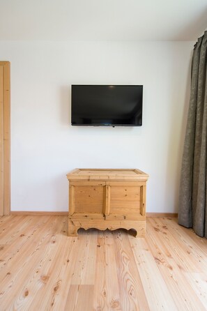 Ein Zimmer mit einem Holzkasten, einem flachbildfernseher an der Wand und einem Holzboden.