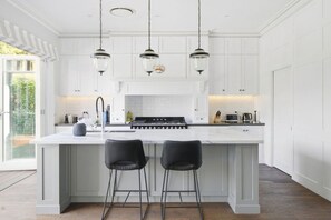 A kitchen with a large island, white cabinetry, and three pendant lights. - Spacious 4-Bed House with Pool in Mosman (Mosman)