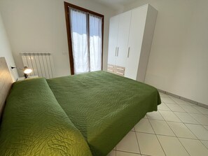 A bedroom with a bed, a window with curtains, a radiator, and a wardrobe. - Spacious home with pool and terraces (Provincia di Rovigo)