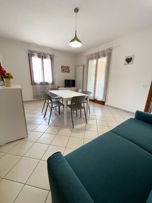 A dining area with a white table and chairs, a television, and a sofa in the foreground. - Spacious home with pool and terraces (Provincia di Rovigo)