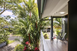 A covered outdoor area with a seating arrangement and a view of the surrounding greenery.